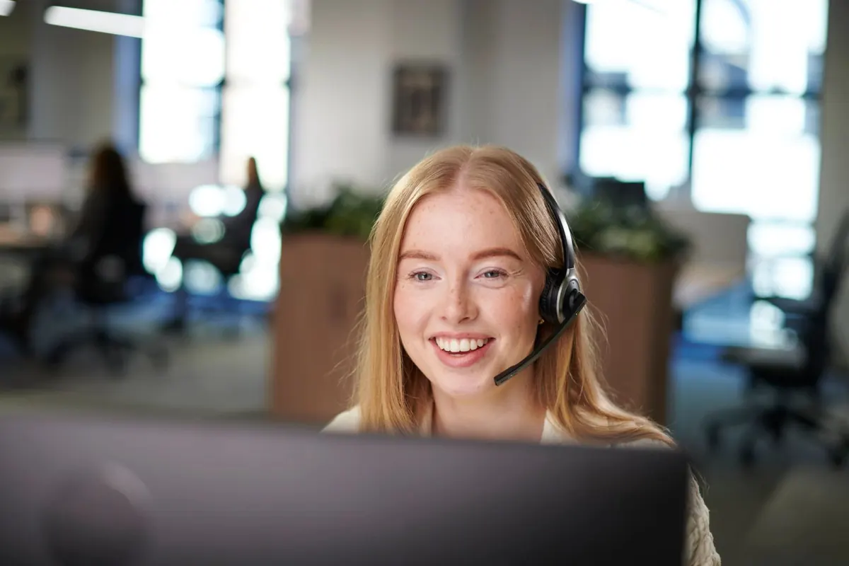 Smiling customer support agent wearing a headset in an office