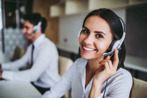 Smiling female call center agent wearing headset at work.