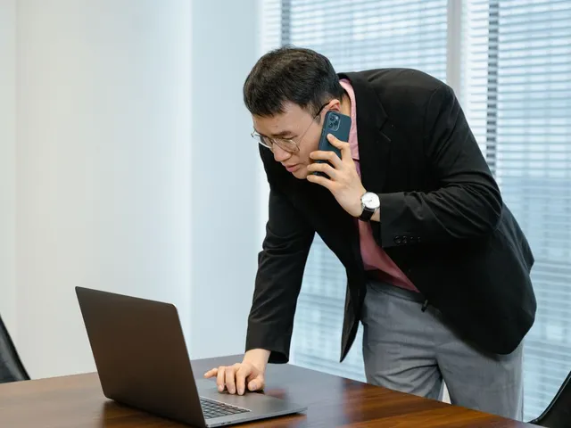 Man on a phone call while working on his laptop.